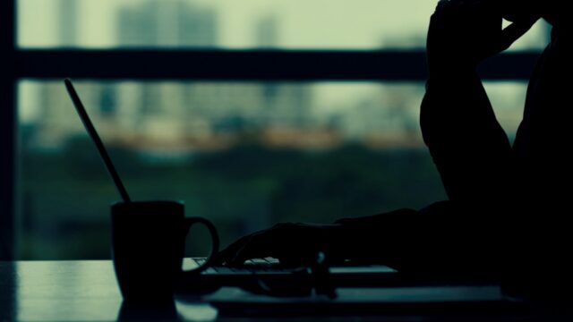 Silhouette of a person working at a desk with a city skyline in the background, representing brand authority and distributed presence for GEO strategy