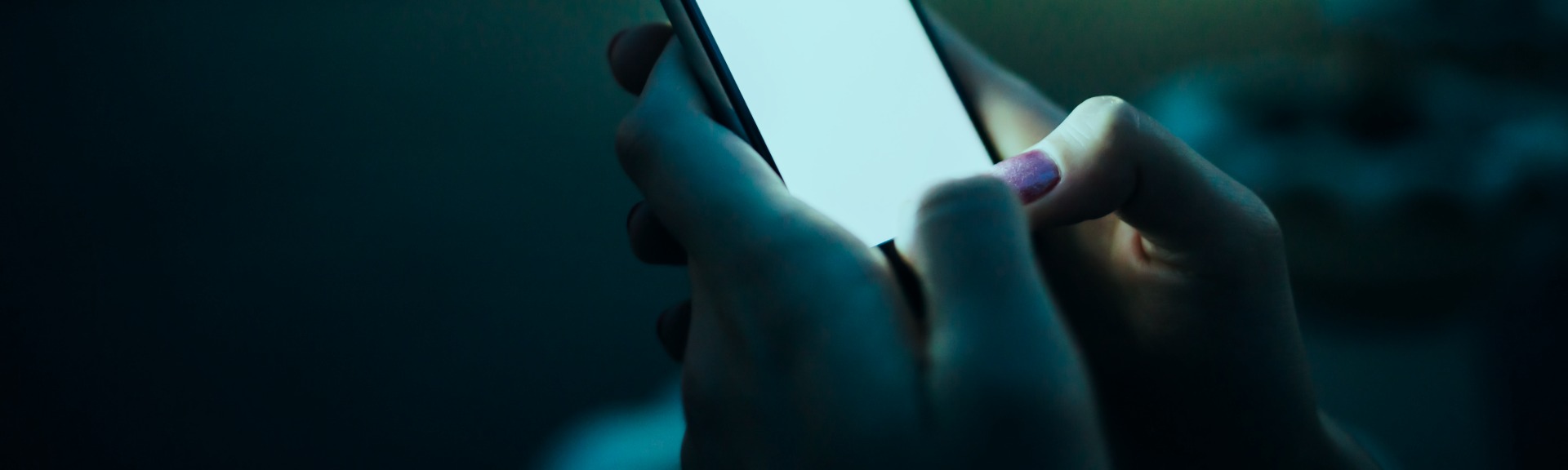 Hand holding a glowing phone screen in dark surroundings, representing buyer search behavior and AI visibility tracking for AEO measurement